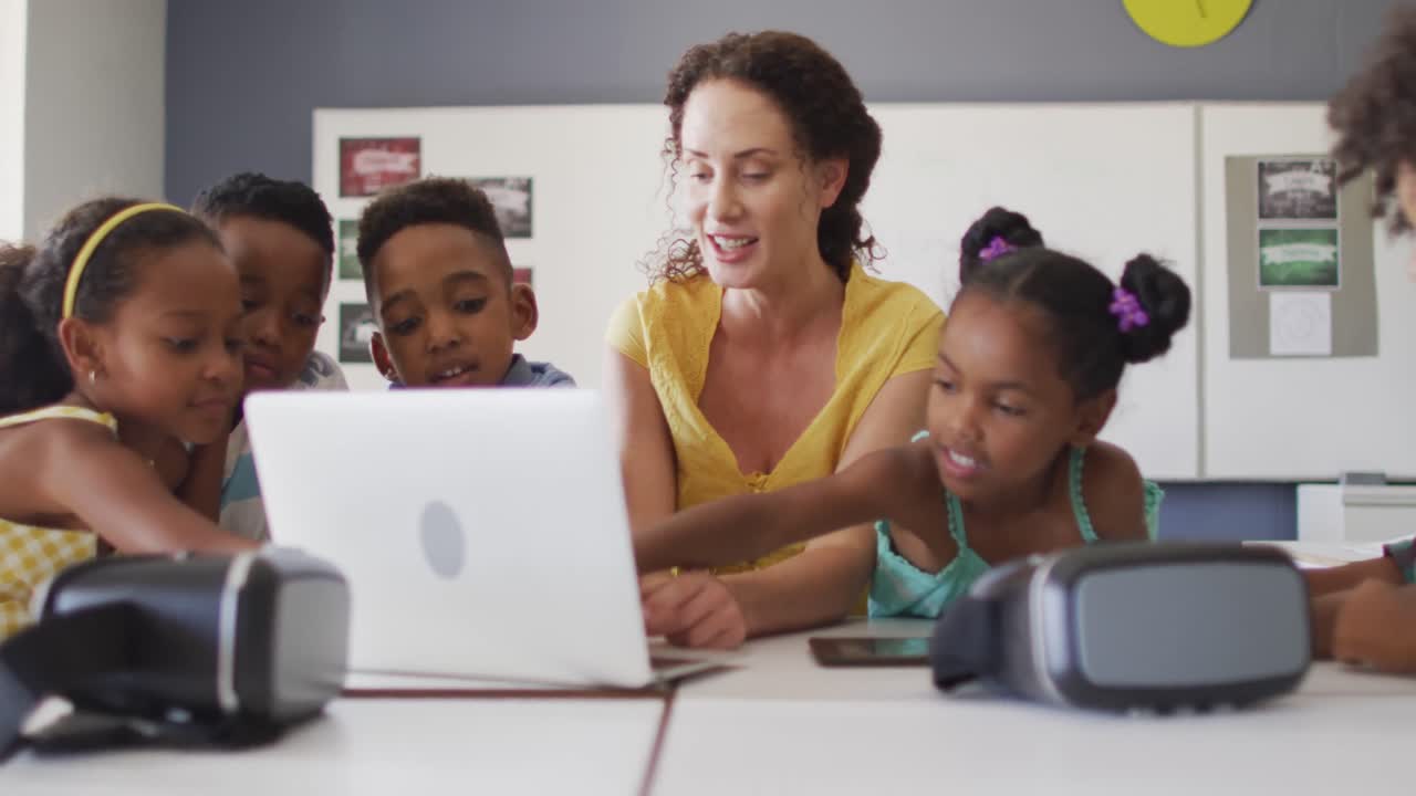 Video of happy caucasian female teacher and african american pupils using laptop and vr headsets