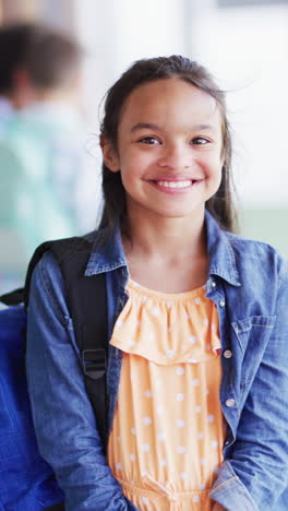 vertical video of portrait of happy biracial schoolgirl in school