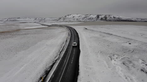 Aerial-drone-follow-shot-of-a-car-driving-on-a-snow-road