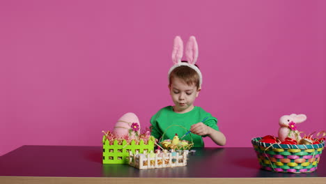 Happy-small-child-arranging-eggs-and-chick-in-a-basket-in-preparation-for-easter