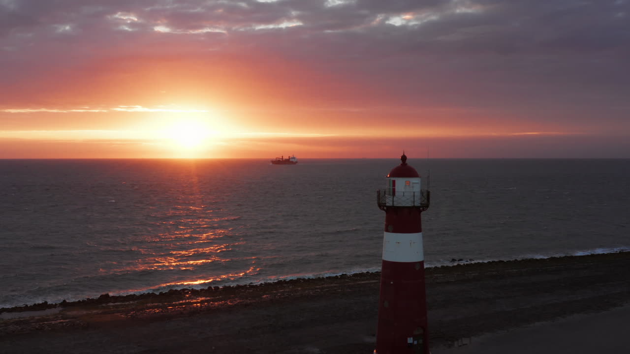 el faro de westkapelle durante una puesta de sol naranja brillante, con mucho viento