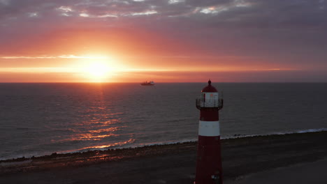 The-lighthouse-of-Westkapelle-during-a-bright-orange-sunset,-with-a-lot-of-wind