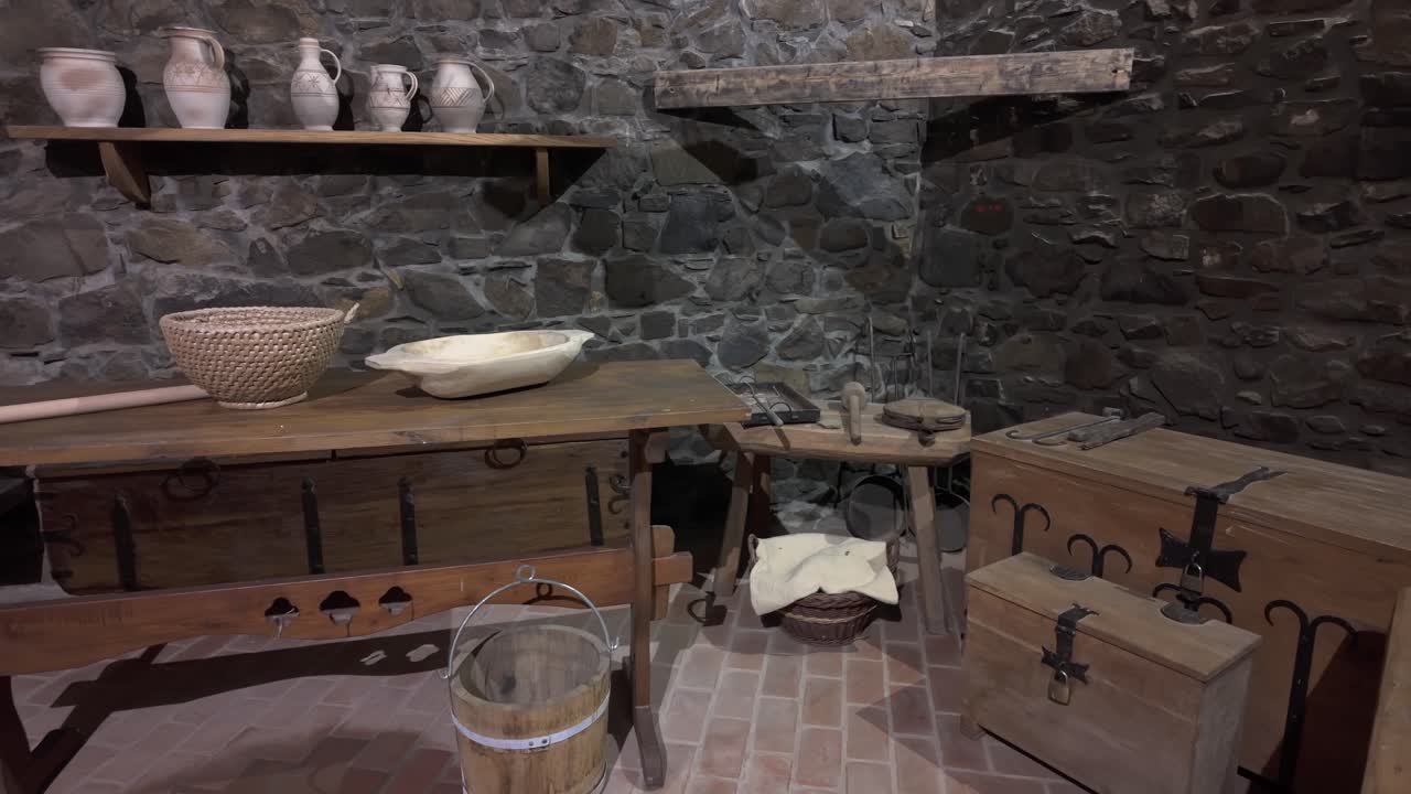 A medieval storage room inside Hollókő Castle with wooden chests, pottery, and stone walls, reflecting historical craftsmanship and daily life in a medieval castle.