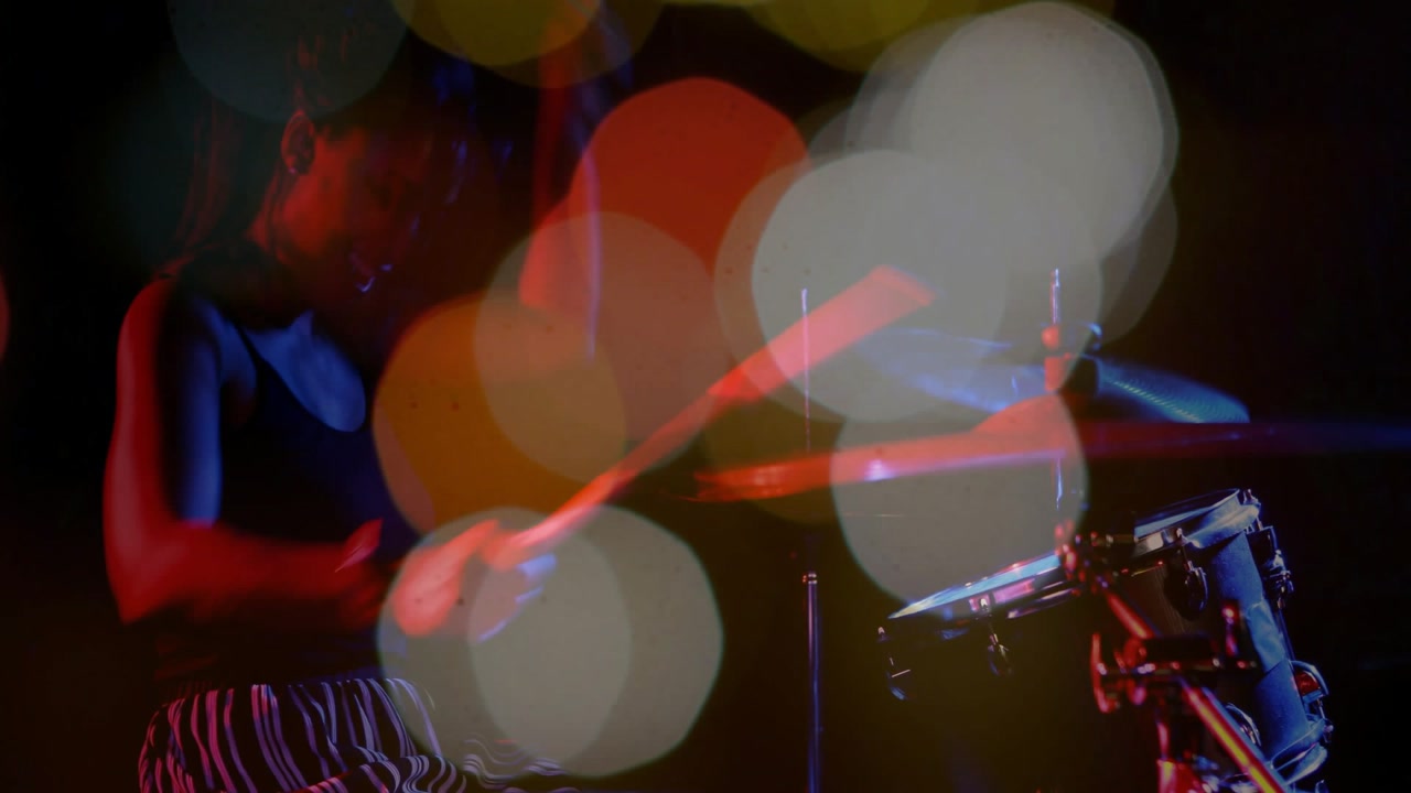 Female drummer lifting drumsticks and striking cymbals in music shoot, animated bokeh overlapping