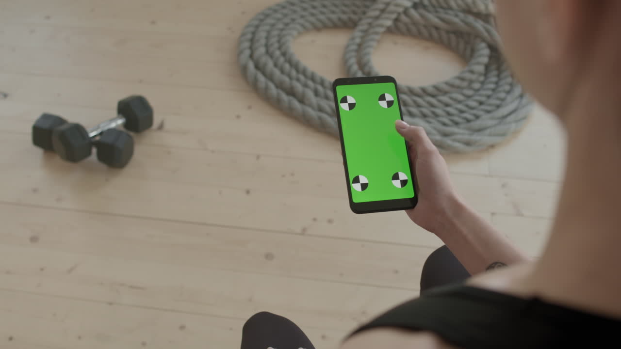 Sportswoman Scrolling Feed On Smartphone At Workout