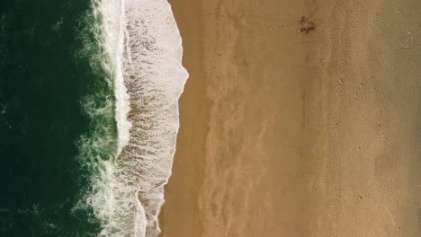 A-birds-eye-view-of-waves-washing-a-shore-in-Devon-Uk