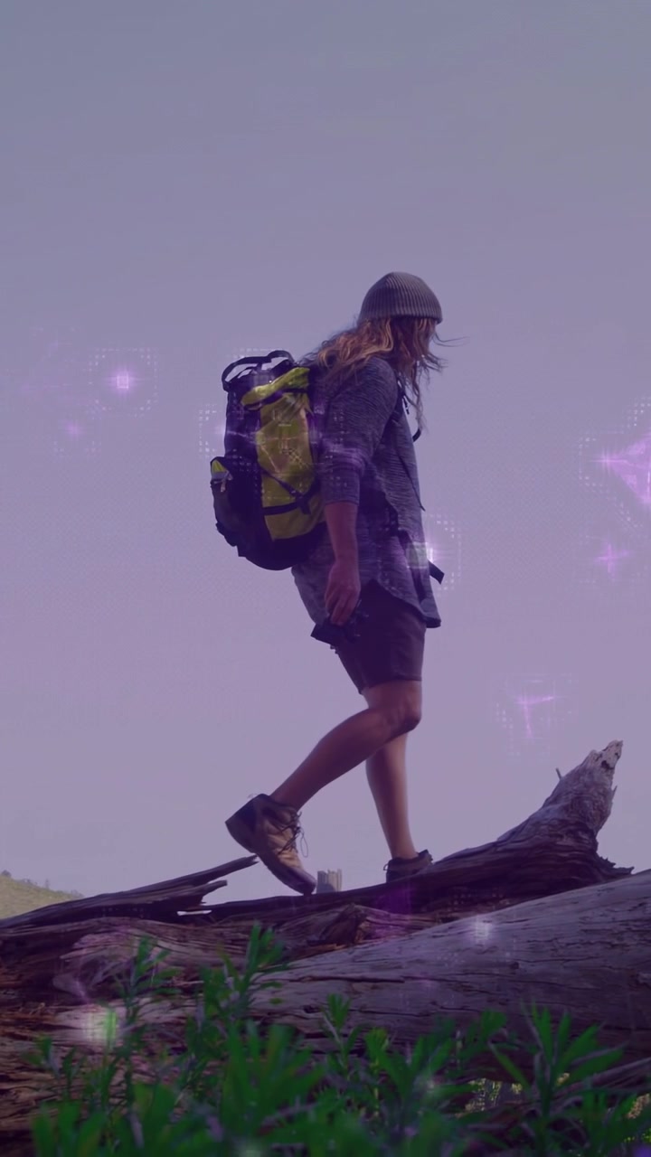 Vertikales Video: Wanderer tritt auf Baumstamm, balanciert und geht über Hügel, mit lila Overlay.