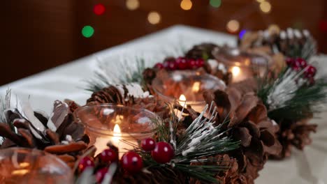 Close-up-shot-of-burning-tea-lights-in-a-Christmas-decoration-of-fir-cones