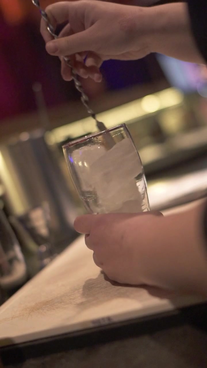 Primo piano di un barista che raffredda un bicchiere mescolando il ghiaccio mentre prepara un cocktail a una festa. Argentina.
