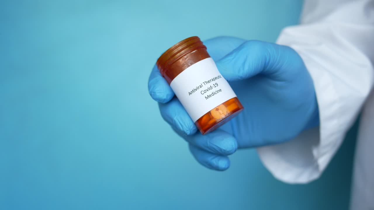 Médico sosteniendo un envase de medicamento antiviral para COVID-19