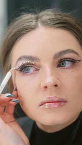 close-up of woman applying rhinestones for eye makeup
