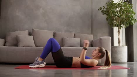 chica caucásica flexible haciendo gimnasia realizando puente acrobático en cámara lenta en casa frente al sofá gris. loft intetior habitación. estilo de vida saludable y deportivo