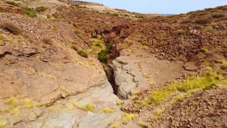 River-flowing-into-deep-valley-of-Tenerife-island,-aerial-drone-view