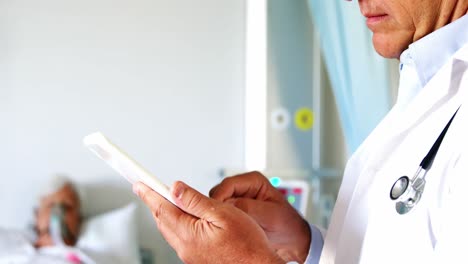 médico masculino usando una tableta digital mientras el paciente mayor se relaja en el fondo