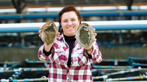 Smiling-caucasian-lady-holds-up-and-displays-two-huge-South-African-abalones