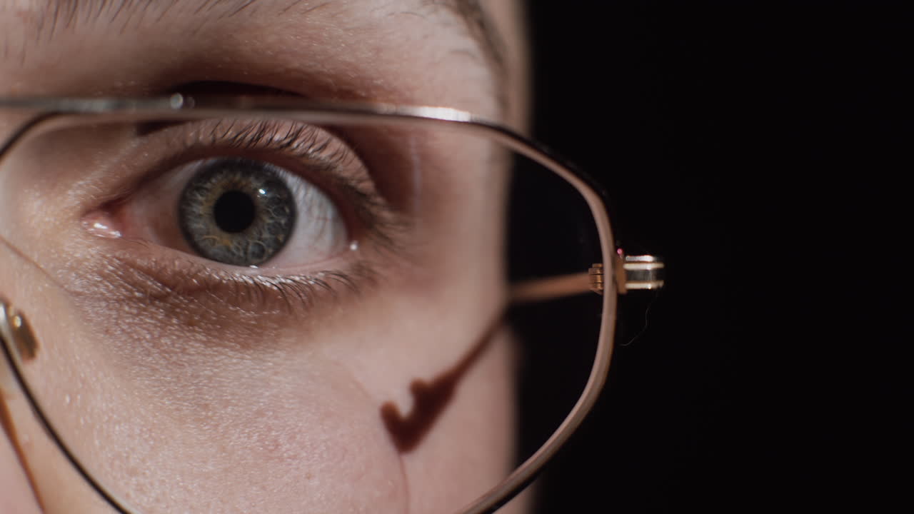 Close-up of a woman's eye with surprised expression wearing vintage glasses
