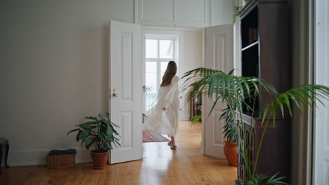 relaxed girl walking at cozy home back view. happy woman spinning around alone