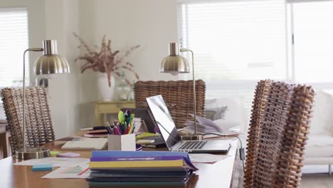 lamps and laptop on busy desk in home office in dining room, slow motion