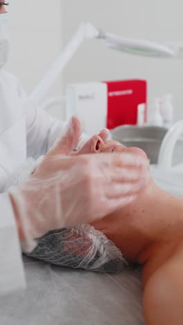 esteticista aplicando crema hidratante especial exfoliando la cara de una bonita mujer caucásica niña