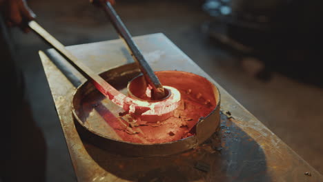 close-up of bending red-hot steel rod into spiral shape on anvil