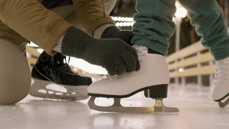 child learning to ice skate with adult assistance