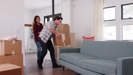 couple carrying removal boxes into new home on moving day