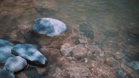 slow-motion shot of rocks under crystal clear water on a calm river