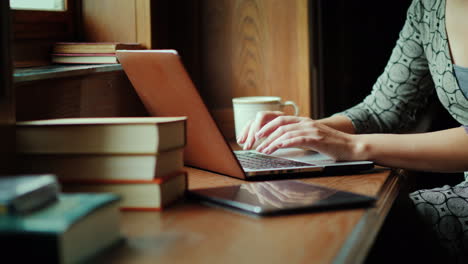 manos escribiendo en una computadora portátil con libros cerca