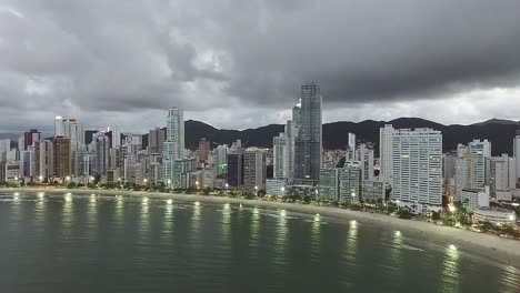 Vista-Aérea-De-La-Ciudad-Turística-Balneario-Camboriú-Junto-Al-Mar-Con-Cordillera-En-Brasil