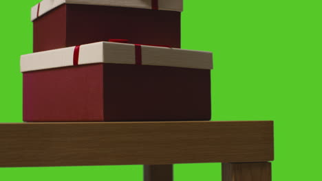 close up of gift wrapped present boxes on table shot against green screen