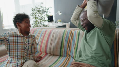 Padre-Afroamericano-E-Hijo-Teniendo-Pelea-De-Almohadas-En-El-Sofá-En-Casa