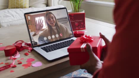 Happy-caucasian-woman-waving-and-making-valentine's-day-video-call-on-laptop