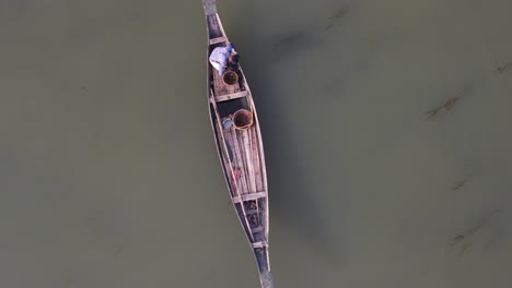 aerial overhead view of lone fisherman on traditional wooden boat floating on the ichamati river