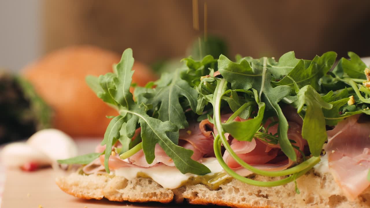 Mortadella ham sandwich, Traditional italian focaccia filled with thin pesto slices of mortadella, served by chef man in cafe restaurant. Macro of traditional italian spanish tapas antipasti.