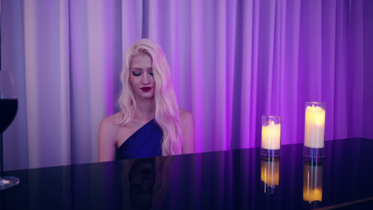 Caucasian Woman in Classic Dress Playing Piano in a Pub or Night Club Lounge Lit with Purple Blue Lights - gimbal dynamic shot