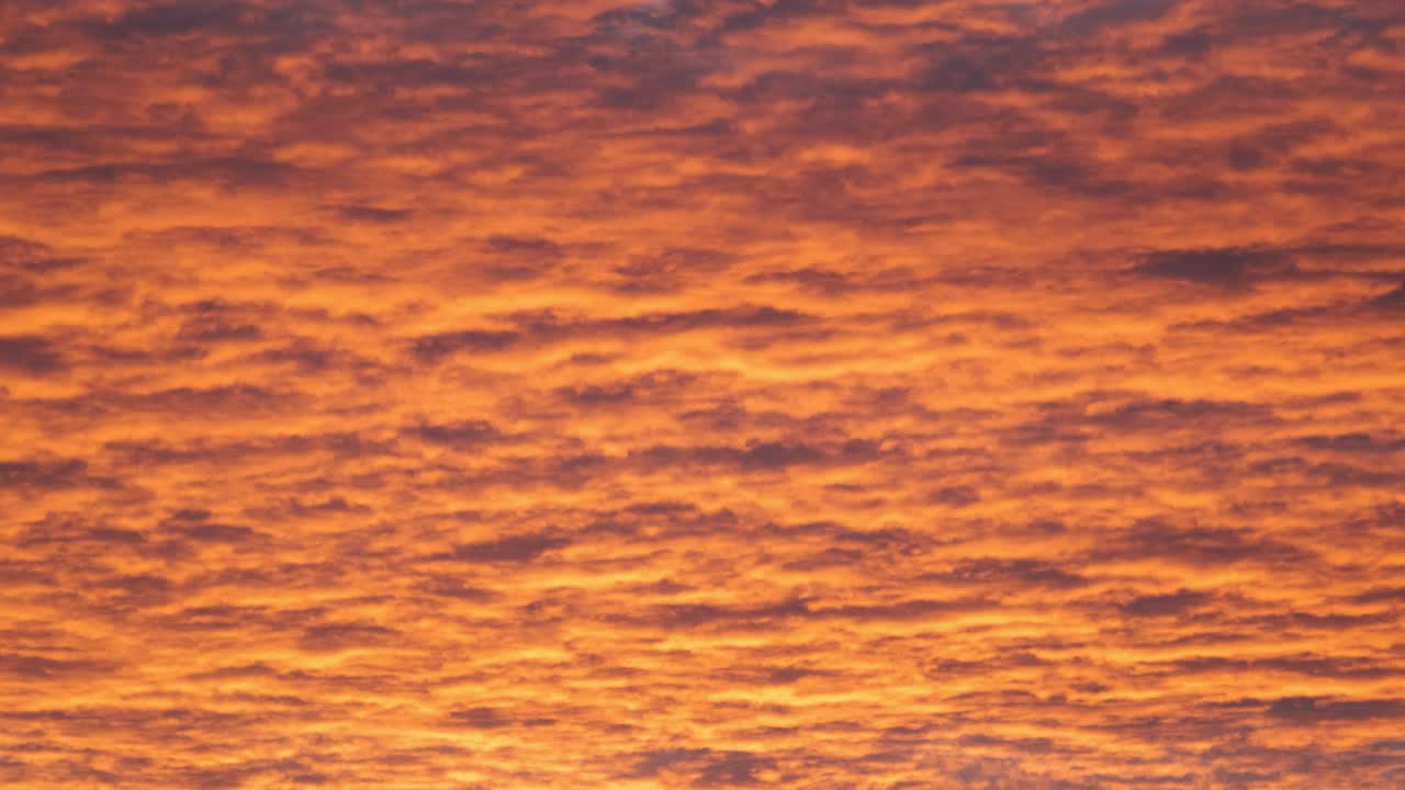 밝고 다채로운 해가 지는 하늘, 생생한 부드러운 구름, 해가 지면으로 퍼지는 빛으로 조명됩니다.