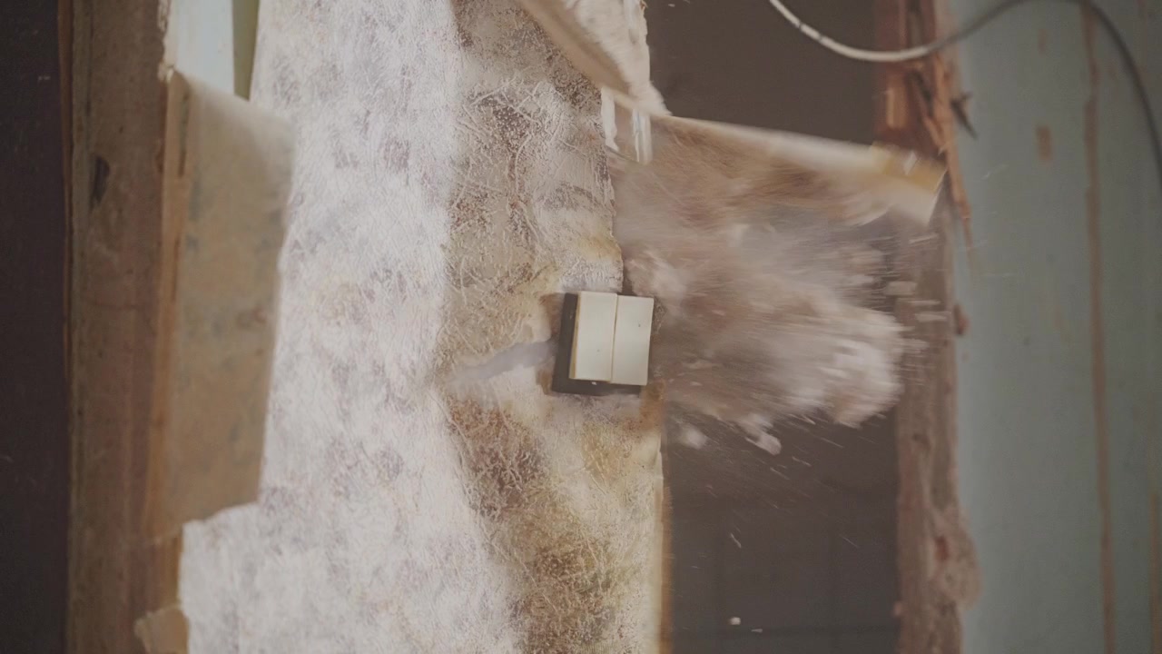 Prach se zvedá, jak demolice interiéru odhaluje skrytou elektroinstalaci a starou omítnutou zeď.