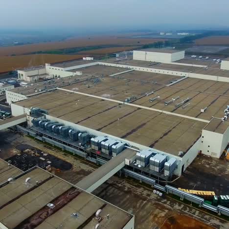 large factory on fields background. industrial zone with car parking among agricultural landscape. motion camera back. aerial view.