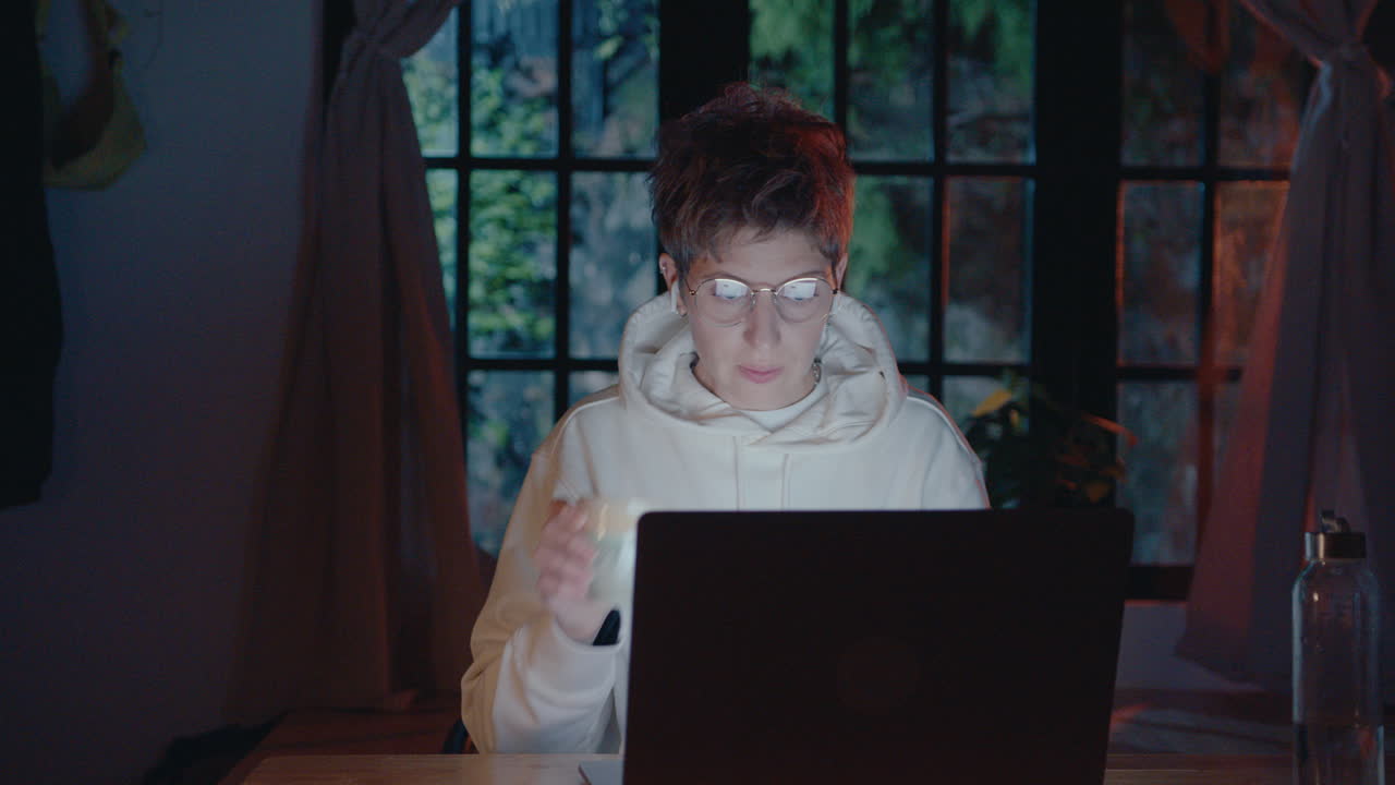 Young Woman Working on Laptop and Drinking Tea in the Evening