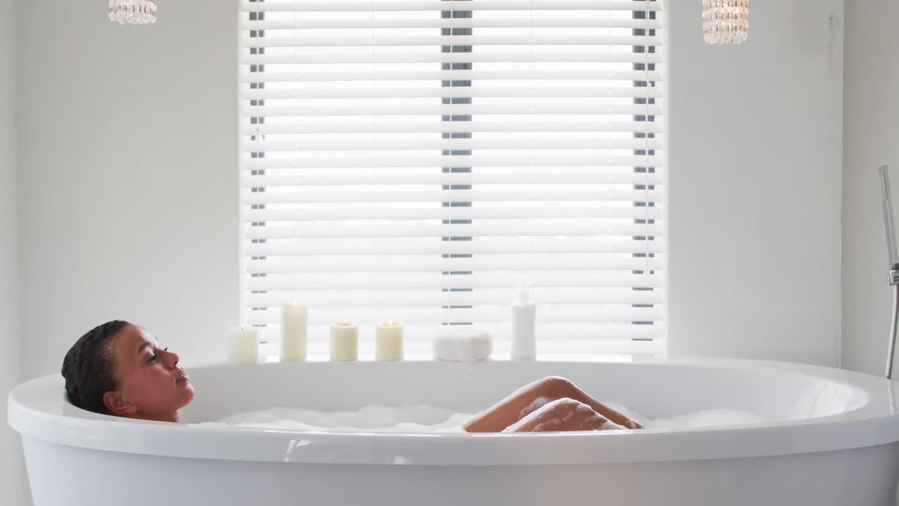 아프리카계 미국인 여성이 집에서 욕조에서 목욕을 하고 있습니다.