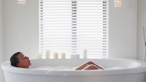 African-american-woman-bathing-in-the-bath-tub-in-the-bathroom-at-home