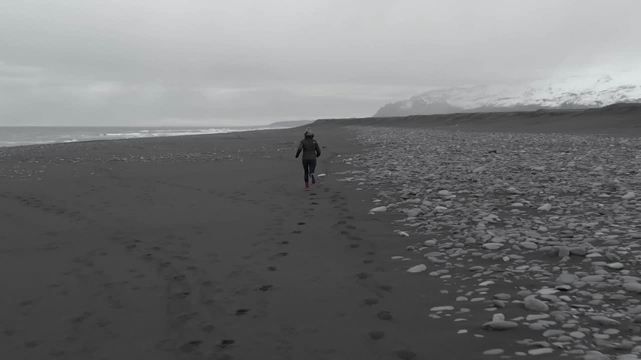 toma aérea cercana de una mujer corriendo por una playa fría