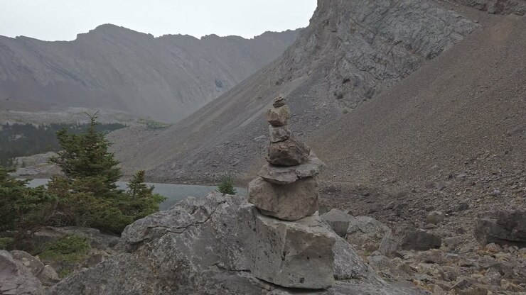 Cairn di roccia in primo piano, escursionisti in avvicinamento sullo sfondo. Montagne Rocciose, Kananaskis, Alberta, Canada.