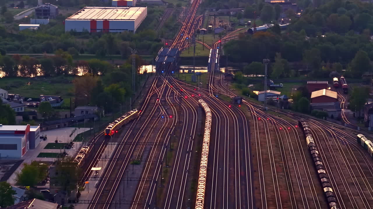 Railway junction with many converging train tracks at dusk lighting, drone view