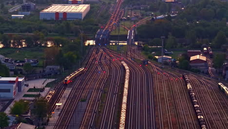 railway junction with many converging train tracks at dusk lighting, drone view