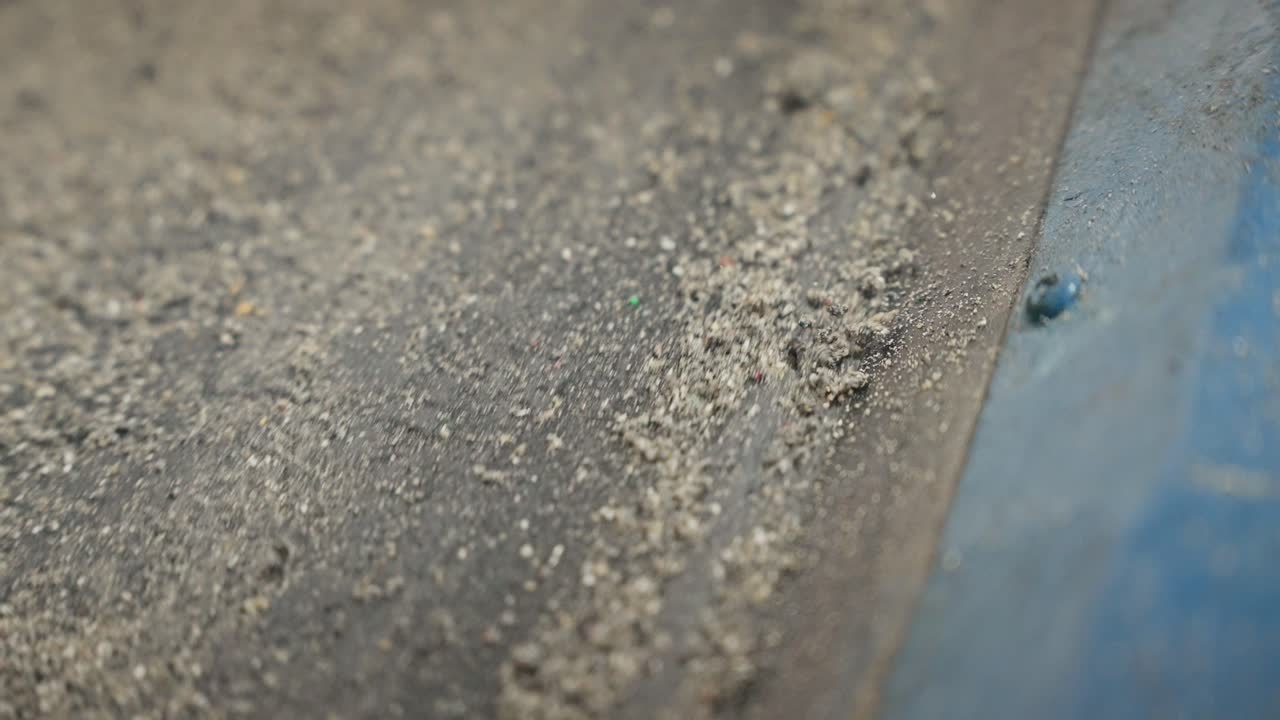 낡은 산업용 컨베이어 벨트 위에서 고무 알갱이가 움직이는 모습을 클로즈업한 영상