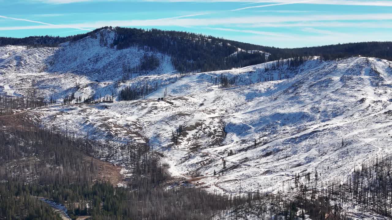 Aerial view of snowy Sierra Nevada mountain landscape with forest fire damage and winding roads