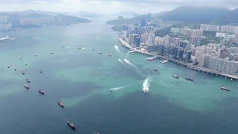 convoy de barcos de pesca locales que causan en la bahía victoria de hong kong, con el horizonte de la ciudad en el horizonte, vista aérea