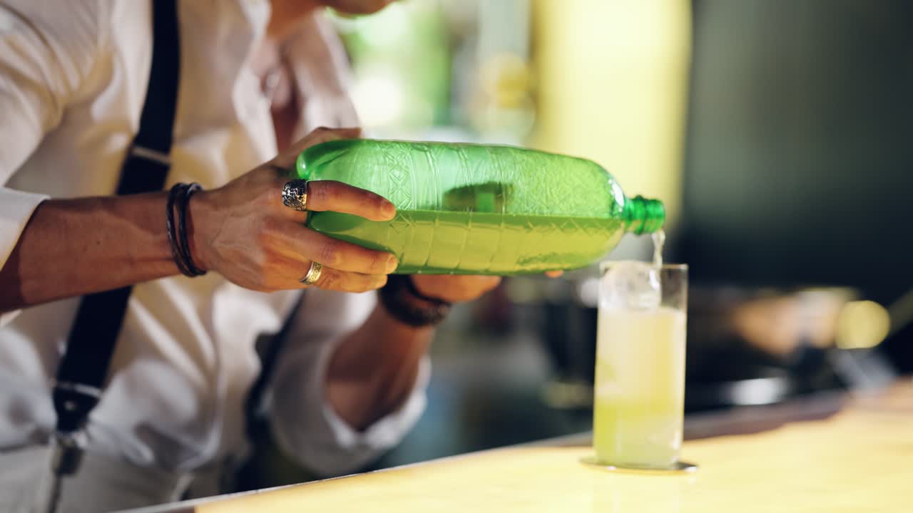 Bartender Pouring Refreshing Drink from Green Bottle into Glass with Ice