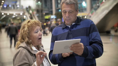 mature couple with tablet pc in public place